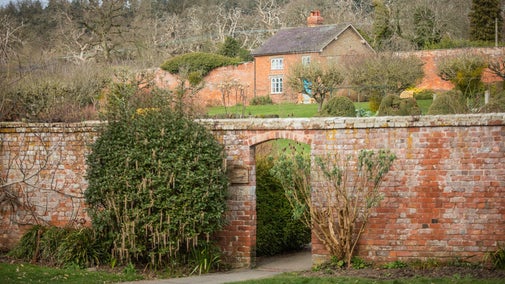 A picture of the entrance to the walled garden. You can see over the top of the wall and into the bare winter garden with a small house at the top on the garden.